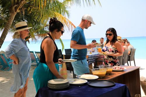 a group of people standing around a table with food at Blue Coral Vashafaru Maldives in Vashafaru