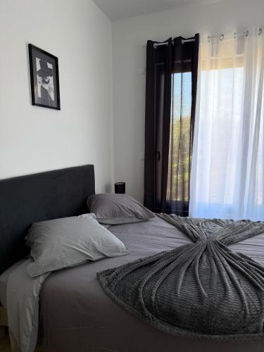 a bed with a comforter and pillows and a window at EXCEPTIONNEL Appartement VERSAILLES in Rocquencourt