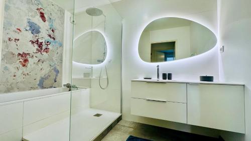 une salle de bain blanche avec un lavabo et un miroir dans l'établissement Oppidum Clim et Parking avec Terrasse de 30 m2 YourHostHelper, à Lattes