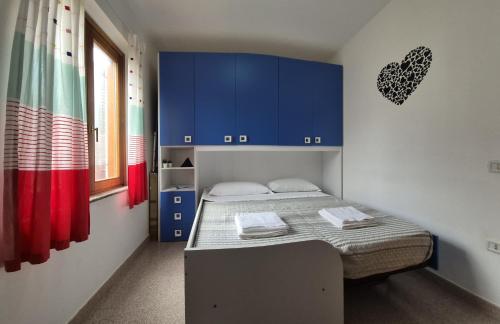 a small room with a bed and blue cabinets at Luce in Santa Maria Navarrese