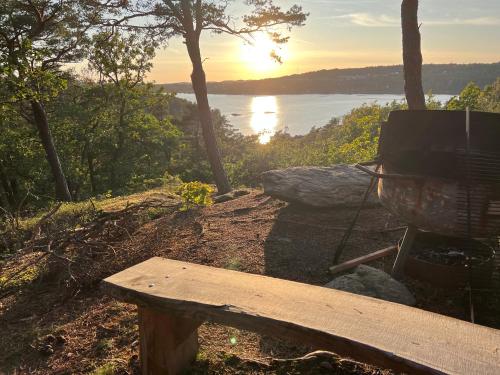 a bench sitting on a hill with a view of the water at Hällesdalens Gård - semesterhus i Bohuslän in Svenshögen