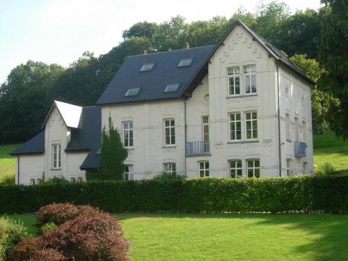 una gran casa blanca con techo negro en House adjoining mansion for a pleasant stay in the region of Chimay, en Plagneau