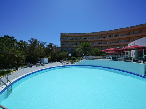 a large swimming pool in front of a building at Club Esse Roccaruja in Stintino