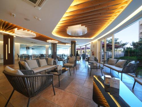 a lobby with couches and tables and chairs at Club Esse Roccaruja in Stintino
