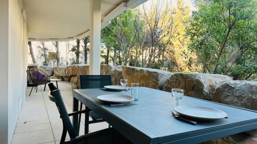 - une table bleue avec des assiettes et des verres à vin sur la terrasse dans l'établissement Oppidum Clim et Parking avec Terrasse de 30 m2 YourHostHelper, à Lattes