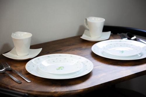 two white plates and two cups on a wooden table at SPU Albergo 井高野 in Osaka