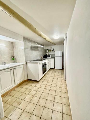 Il comprend une cuisine dotée d'appareils électroménagers blancs et de carrelage. dans l'établissement Le Bien Placé tout confort, à Orange