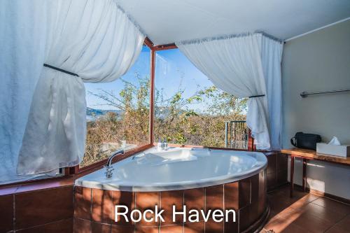 a bath tub in a room with a large window at Thabela Thabeng in Parys