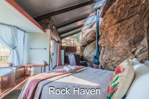 a bedroom with a bed and a rock wall at Thabela Thabeng in Parys
