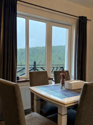 a table with chairs and a book on it with a window at Мелодія Гір .Апартаменти з видом на гори . in Vorokhta