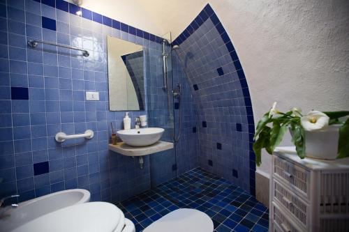 bagno piastrellato blu con lavandino e servizi igienici di Residence Guidaloca a Scopello
