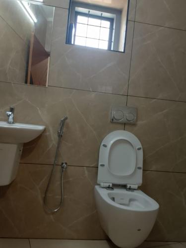 a bathroom with a toilet and a sink and a window at Misty Rosa Resorts Pvt Ltd in Kottayam