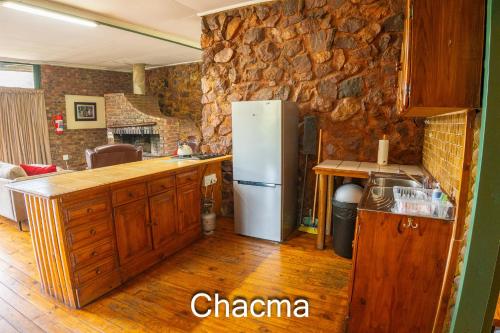 a kitchen with a refrigerator and a stone wall at Thabela Thabeng in Parys