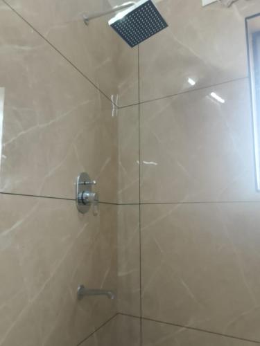 a shower with a glass door with a shower head at Misty Rosa Resorts Pvt Ltd in Kottayam