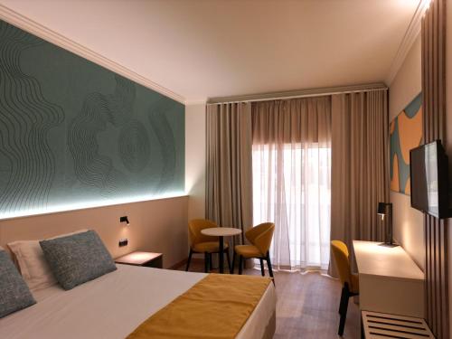 a hotel room with a bed and a desk at Ukino Palmeiras Village - 24h All Inclusive in Armação de Pêra