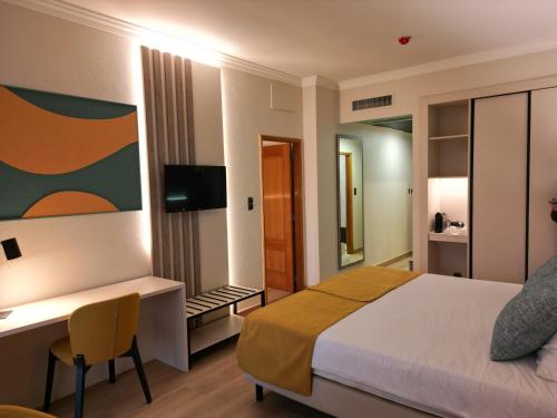a bedroom with a bed and a desk and a television at Ukino Palmeiras Village - 24h All Inclusive in Armação de Pêra