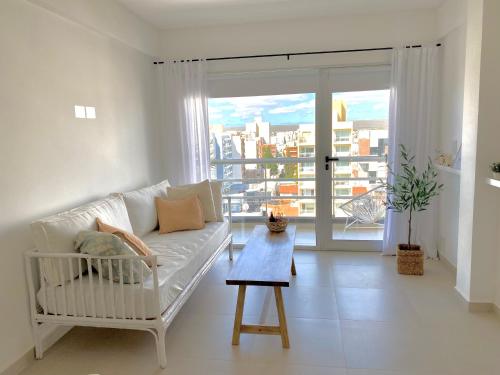 un salon avec un canapé blanc et une grande fenêtre dans l'établissement FIKA - Depto Temporario, à Puerto Madryn