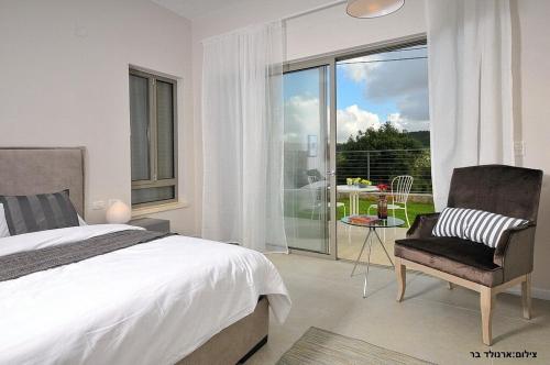 a bedroom with a bed and a chair and a window at Malki House- a whole complex just for you in Lappidot