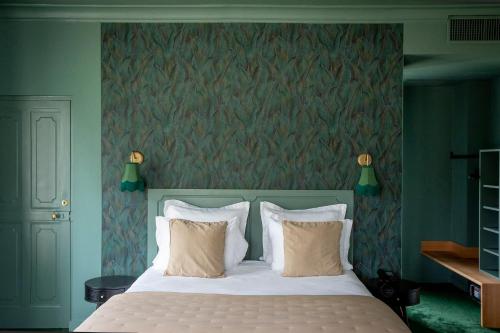 a bedroom with a white bed with a green wall at Les Hayes en Sologne in Fontaines-en-Sologne