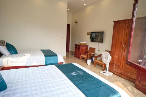 a bedroom with two beds and a desk and a television at Kim's Family Hotel in Ha Long