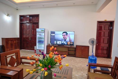 a living room with a television and a table with flowers at Kim's Family Hotel in Ha Long