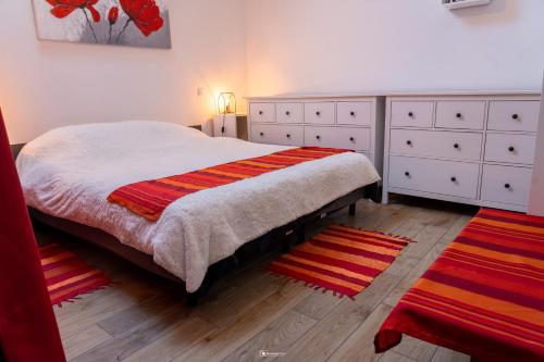 - une chambre avec un lit doté de robes blanches et de tapis rouges dans l'établissement Gîte des dolmens 3 etoiles, à Saint-Quay-Portrieux