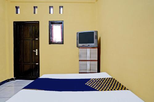 a room with a bed and a tv and a door at OYO Life 91947 Kost Barokah Syariah in Mojokerto