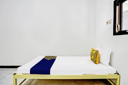 a bed with a blue and yellow blanket on it at OYO Life 91947 Kost Barokah Syariah in Mojokerto