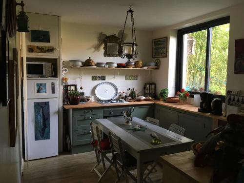 une cuisine avec une table et un réfrigérateur blanc dans l'établissement Très jolie maison d'artiste,jardin,proche mer, à La Rochelle