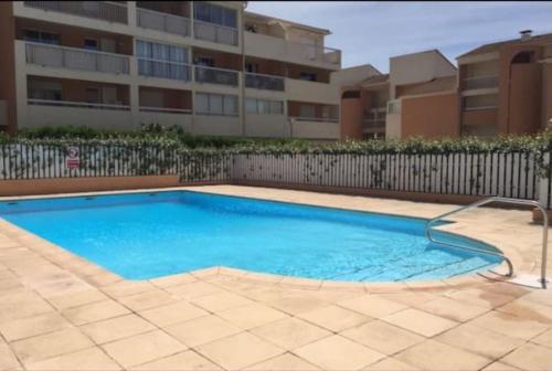 une grande piscine bleue devant un immeuble dans l'établissement Charmant cocon, vue mer, piscine et clim, à La Seyne-sur-Mer