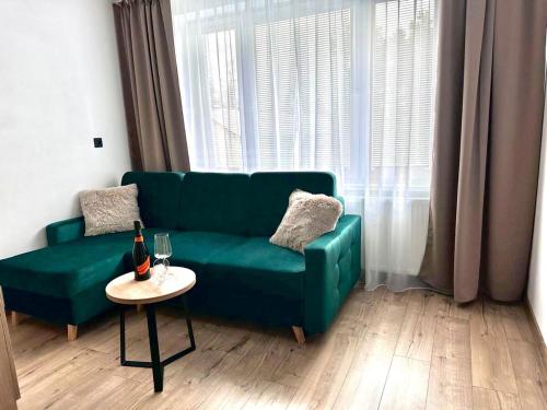 a green couch in a living room with a table at Apartmán Luxe Brezno center in Brezno