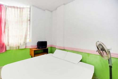 a room with two beds and a fan and a window at Hotel O Penginapan Saweri GadingNearKlub Golf Ria Bintan in Nagoya