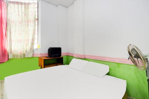 a bedroom with two white beds and a fan at Hotel O Penginapan Saweri GadingNearKlub Golf Ria Bintan in Nagoya