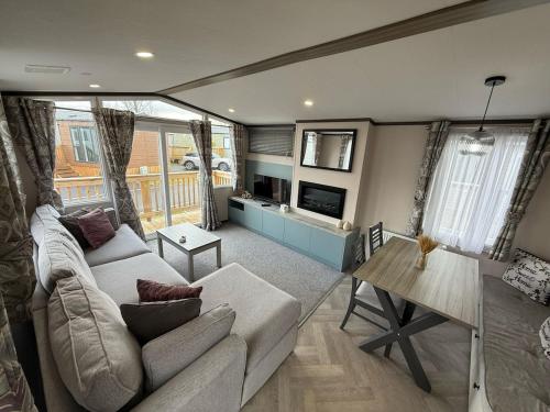 un salon avec un canapé et une table dans l'établissement Grey Goose Lodge with hot tub at Brickyard Lakes, à Amotherby