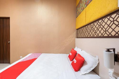 a bedroom with a bed with red and white pillows at Flagship 91863 Metro House in Putat-wetan