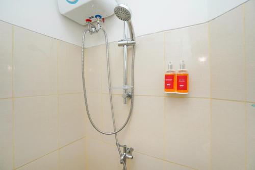 a shower with a shower head in a bathroom at Capital O 91962 Pavilion Permata Surabaya in Dukuhpakis