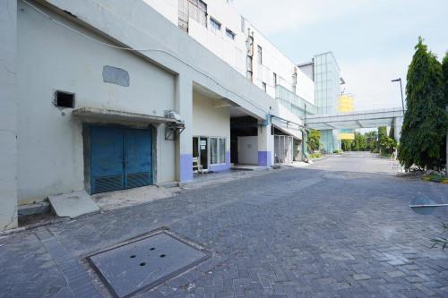 an empty street next to a building with a blue door at Capital O 91962 Pavilion Permata Surabaya in Dukuhpakis