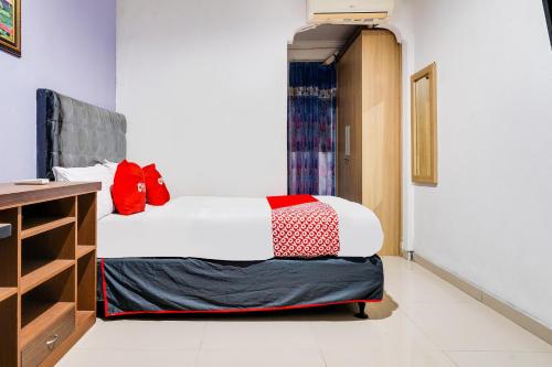 a bedroom with a bed with white sheets and red pillows at OYO Life 91994 Sawerigading Jatinangor Syariah in Sayang