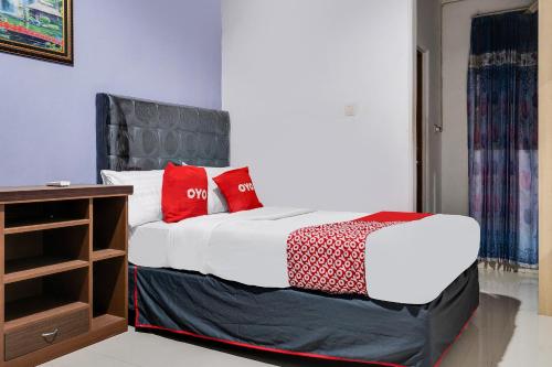 a bedroom with a bed with red pillows on it at OYO Life 91994 Sawerigading Jatinangor Syariah in Sayang