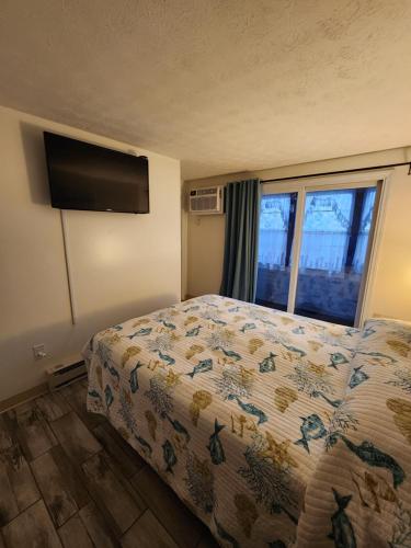 a bedroom with a bed and a flat screen tv at Nautical Mile Resort in Wells
