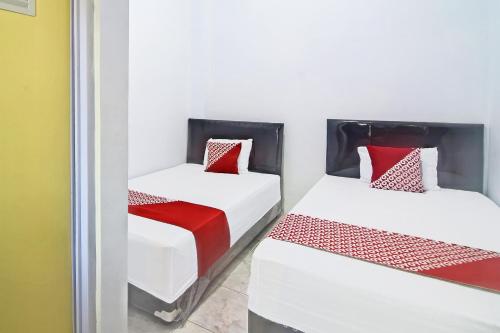 two beds with red and white sheets in a room at Hotel O Cvictory Inn in Manado