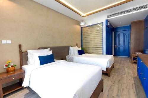 two beds in a hotel room with blue accents at LCV Mũi Né Resort in Mui Ne