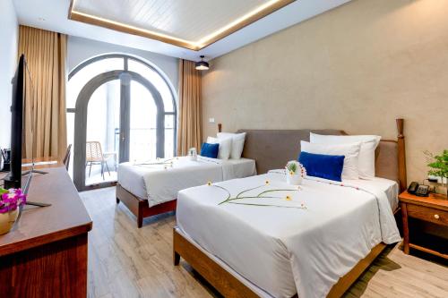 a hotel room with two beds and a television at LCV Mũi Né Resort in Mui Ne