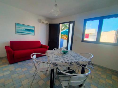 a living room with a table and a red couch at La Casa del Marinaio P1 in San Foca