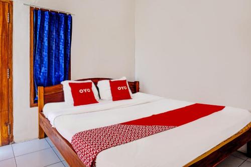 a bedroom with a bed with two red pillows at OYO Life 92021 Dua Putra Homestay Klayar in Watukarung