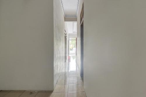 a hallway with white walls and a tile floor at Hotel O Borneo in Manado