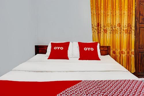 a bedroom with a bed with two red pillows at OYO Life 92021 Dua Putra Homestay Klayar in Watukarung