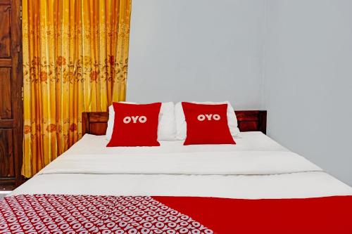 a bed with two red pillows on it at OYO Life 92021 Dua Putra Homestay Klayar in Watukarung