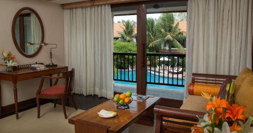 a living room with a table and a view of a pool at Radisson Blu Resort Temple Bay Mamallapuram in Mahabalipuram