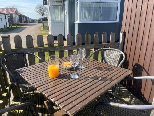 a wooden table with glasses and a plate of food on it at Seaside Escape Chalet in Bridlington south shore in Bridlington